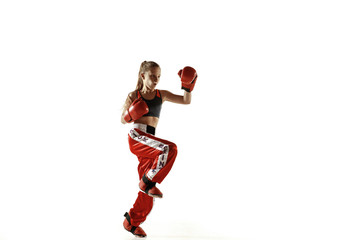 Young female kickboxing fighter training isolated on white background. Caucasian blonde girl in red sportswear practicing in martial arts. Concept of sport, healthy lifestyle, motion, action, youth.