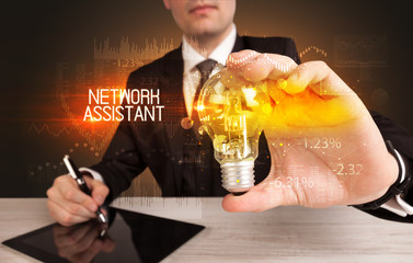 Businessman holding lightbulb with NETWORK ASSISTANT inscription, Business technology concept