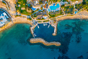 Aerial view of Coral Bay, famous place with sandy beaches near Paphos, Cyprus and rock cliffs with hotel on seaside. Idyllic mediterranean landscape from air.