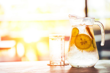 the fruit in the water and ice is on the table. the water in glass near jar.