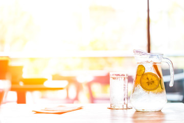 the fruit in the water and ice is on the table. the water in glass near jar.