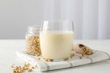 Glass of soy milk, soybeats seeds on white background, space for text. Closeup