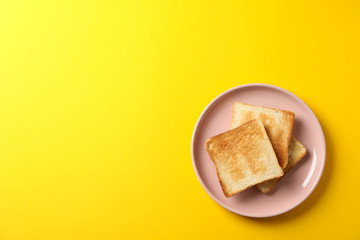 Fototapeta na wymiar Plate with tasty toasts on yellow background, top view