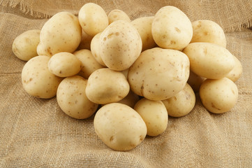 Raw potatoes on burlap sack background