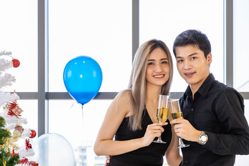 Attractive young couple celebrate Christmas and New Year in party, clinking champagne glass, with snack and beverage on table