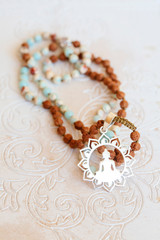 Jewelry mala necklace with natural mineral beads on white wooden decorative background