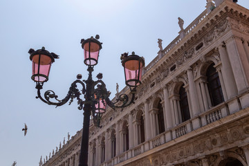 Fototapeta na wymiar Detail of pink lanterns with birds in St Marks Square in front of the national library in venice, Italy