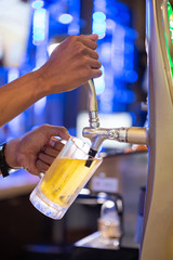 Hand of bartender pouring a large lager beer in tap. Soft,