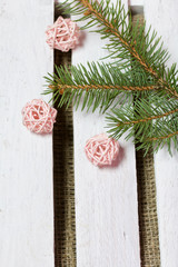 Fir branch and decorative balls on a background of wooden boards. The boards are painted white.