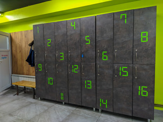 Modern style locker room or dressing room with numbers on lockers in grey and green colors used for changing clothes and safety while in gym or doing sports