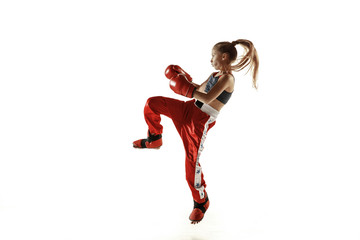 Young female kickboxing fighter training isolated on white background. Caucasian blonde girl in red sportswear practicing in martial arts. Concept of sport, healthy lifestyle, motion, action, youth.