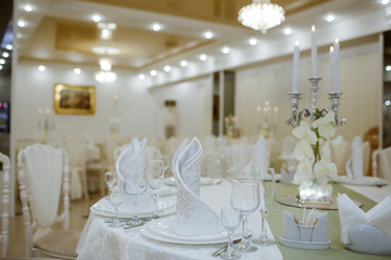 Restaurant decorated with white elements, and tables with crystal dishes.