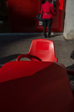  Lady With Red Backs, Taking Out Money In A Red Cashier, With A Red Chair And Table In The Foreground