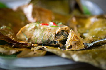 Steamed fish with curry paste in banana leaf wrapped in white dish thai food (Thai language call Hor mok) on gray table