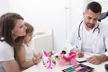 Obraz premium pediatric doctor while working with a child. mother with a child examined by a pediatrician