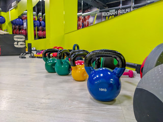 Weight dumbbells in the shape of balls in different colors for strength training and bodybuilding in a modern gym as a healthy lifestyle workout