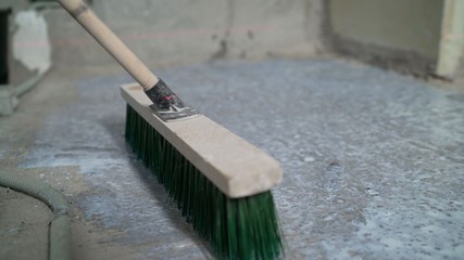 Primer for concrete floor. The master lays liquid soil on a concrete floor. Primer worker on...