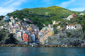 Fototapeta na wymiar Riomaggiore with colorful houses on a warm sunny day. Riomaggiore is one of the five famous coastal village in the Cinque Terre National Park, Liguria, Italy.