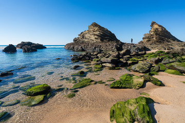 Fototapeta na wymiar Woman on the rocks at Praia da Samoqueira beach in Portugal