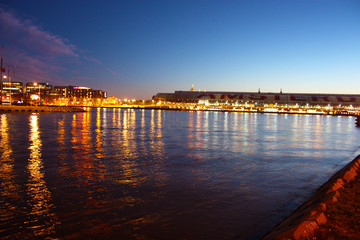 Fototapeta na wymiar Romantic autumnal evening panorama over the canal waters of the Dutch metropolitan city of Amsterdam, among the lights and illuminations of the buildings and skyscrapers