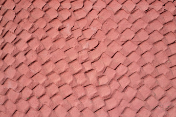 The texture of the plastered wall. Rough corrugated cement surface. Faded red color. Uneven angular pattern. Perfect for background and design.