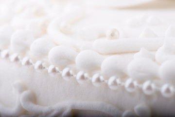 Obraz premium White Wedding cake detail closeup with fondant, swirls, and decorative pearls