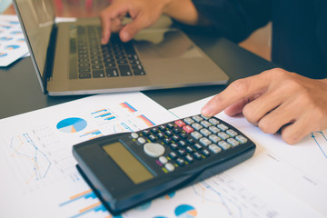 Businessman analysis on Graph data paper  using calculator, finance concept in office.