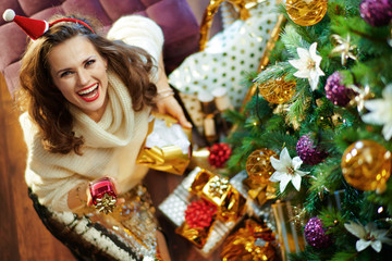 happy stylish woman holding torn present box and facial cream