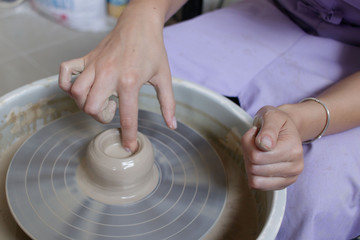hands of potter creating a jar on circle