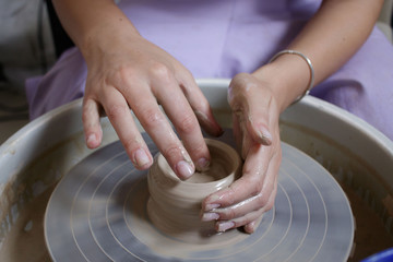 hands of potter creating a jar on circle