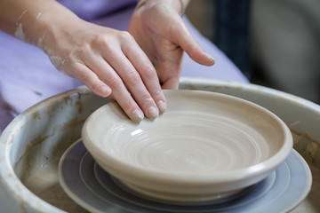 hands of potter creating jar on circle