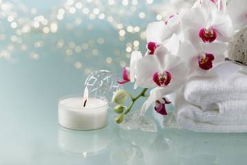 Christmas or spa decoration with white  an orchid, soft towel, burning candle on light background.