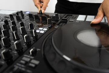 Hands of DJ mixing tracks on professional sound mixer.Fashionable rings on fingers of girl disc jockey playing music.Closeup,knobs and regulators in focus.Girl dj play music tracks at house party