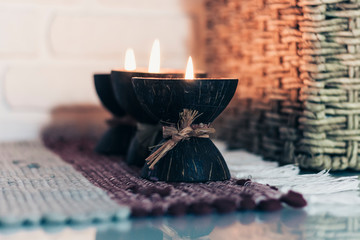 Burning spa aroma candle in coconut shell on a knitted multicolored rug and wicker box with a towel...