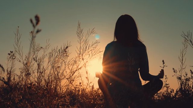 yogi trains morning landscape rays of sun lighting on female calm and healthy outdoors background slow motion