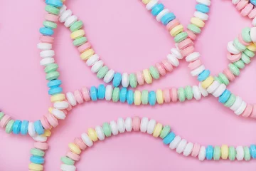 Rolgordijnen Candy necklace on pink pastel colored background. © Olena Bloshchynska