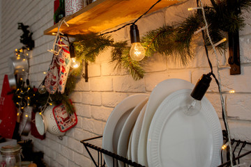 Christmas decoration of the kitchen of the house in the loft style. Decorations with fir branches and garlands