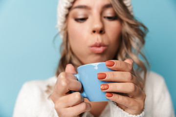 Portrait of blonde attractive woman blowing and holding cup