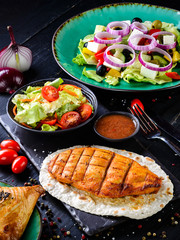 grilled chicken fillet with fresh salad on a dark background