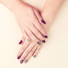 Female hands with creative manicure. Beautiful woman hands on beige background, top view. Manicured nails concept