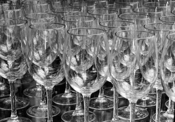 Close up many rows of empty wine glasses black and white color selective focus isolated on black background.