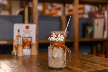 Glass mason jar with ice latte coffee  on wooden table in a coffee shop