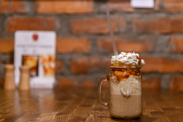 Glass mason jar with ice latte coffee  on wooden table in a coffee shop