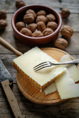 Manchego cheese and nuts on rustic wooden table