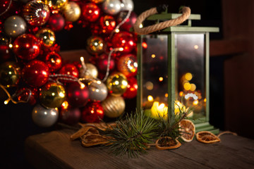 Fototapeta na wymiar Christmas wreath and lantern with candles. December evening. Festive atmosphere.