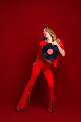 Dynamic shot of a young beautiful sexy woman in a red dress dancing on a red background