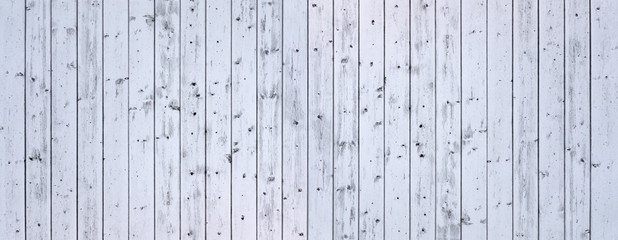 Panorama einer hellgrauen, verschmutzten, verwitterten Holzwand aus vertikalen Brettern