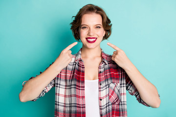 Portrait of positive cheerful girl point index finger on beaming smile show her perfect ideal teeth after medicine clinic wear stylish clothing isolated over teal color background