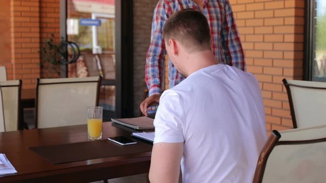 Young businessman makes payment using wireless NSF system in a restaurant