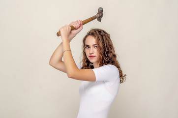 Pretty girl holds a hammer in hands, swings to strike